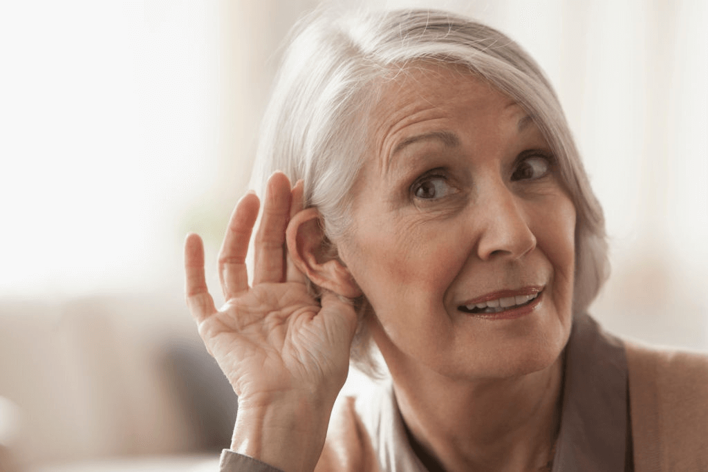 senior caucasian woman cupping her ear to listen