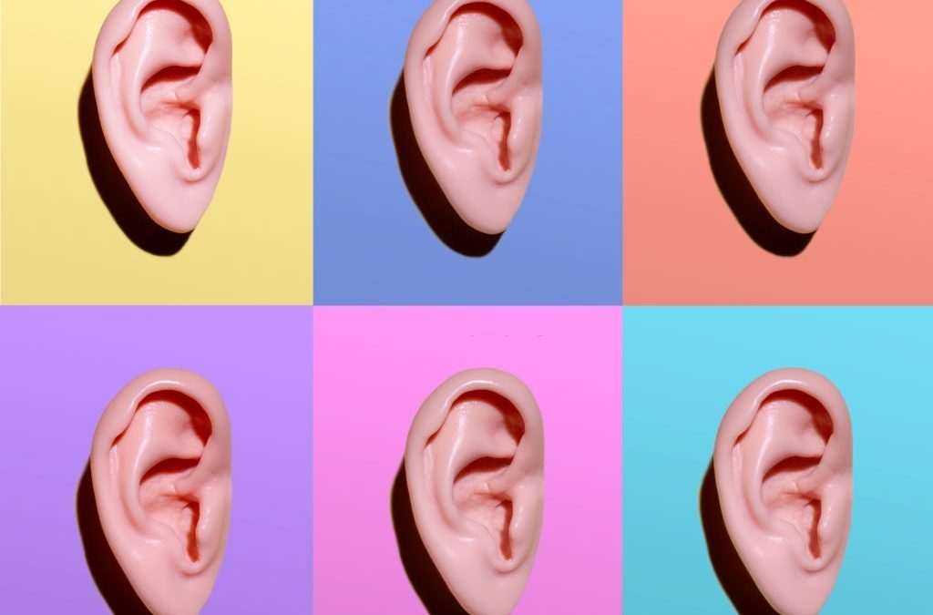 6 realistic models of human ears on various pastel color backgrounds