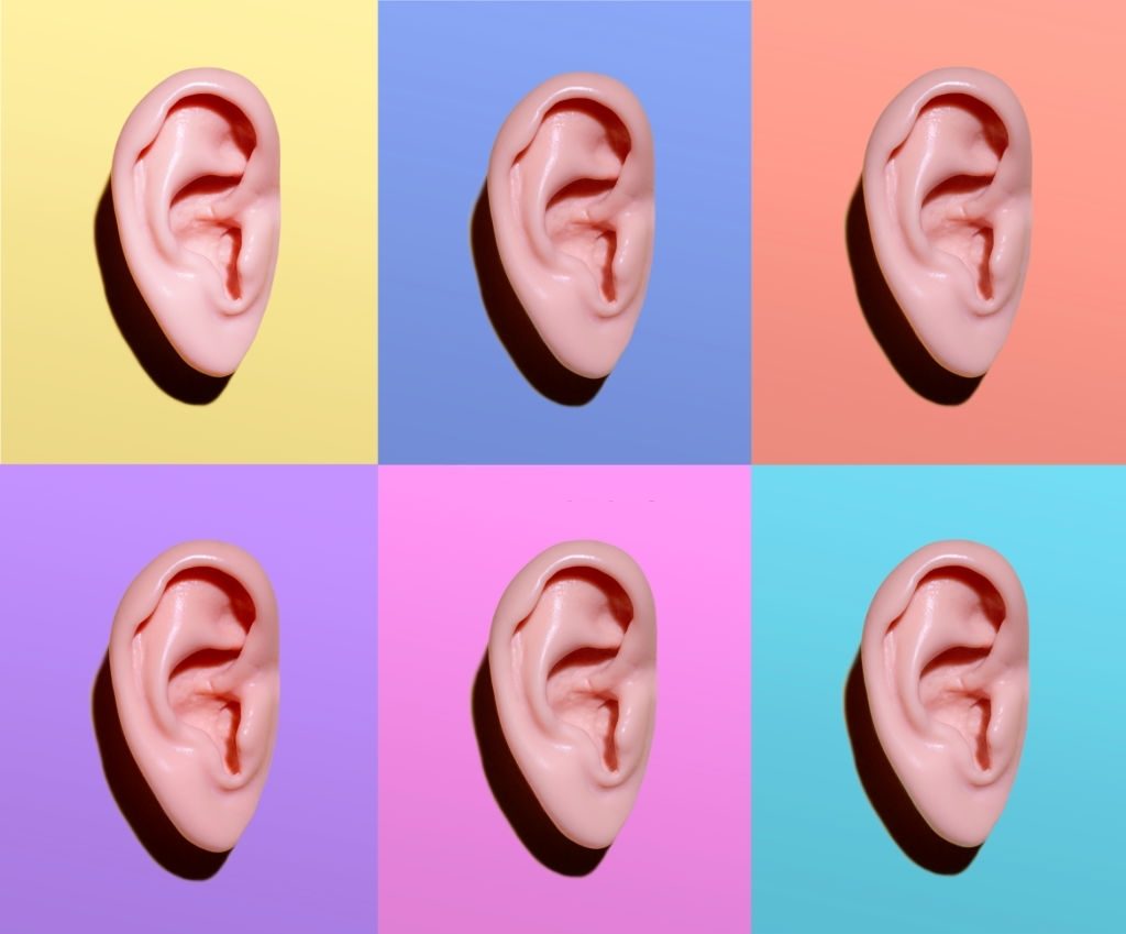 6 realistic models of human ears on various pastel color backgrounds