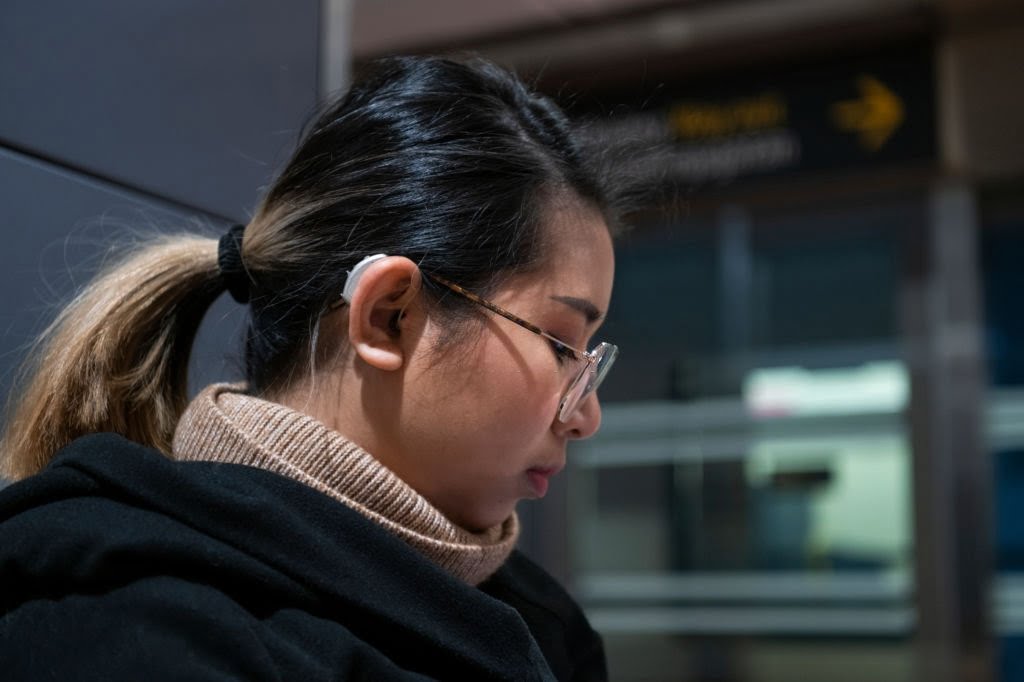 an Asian woman wearing hearing aid at street